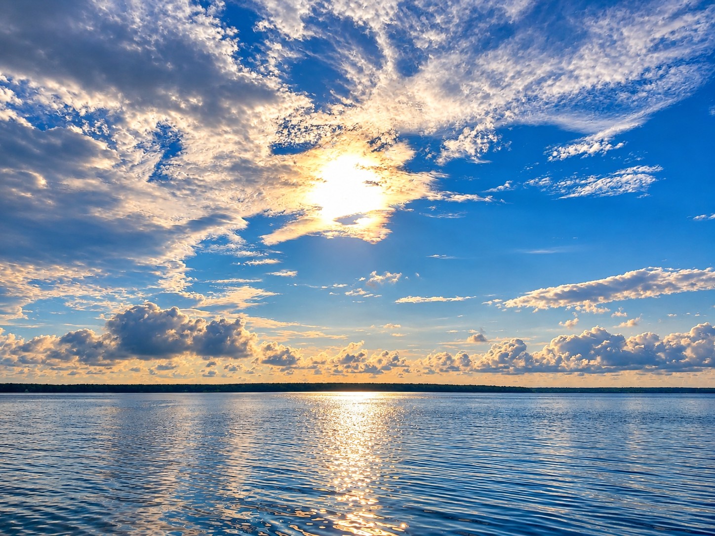 Sun breaking through clouds over the open water of Lake Gogebic